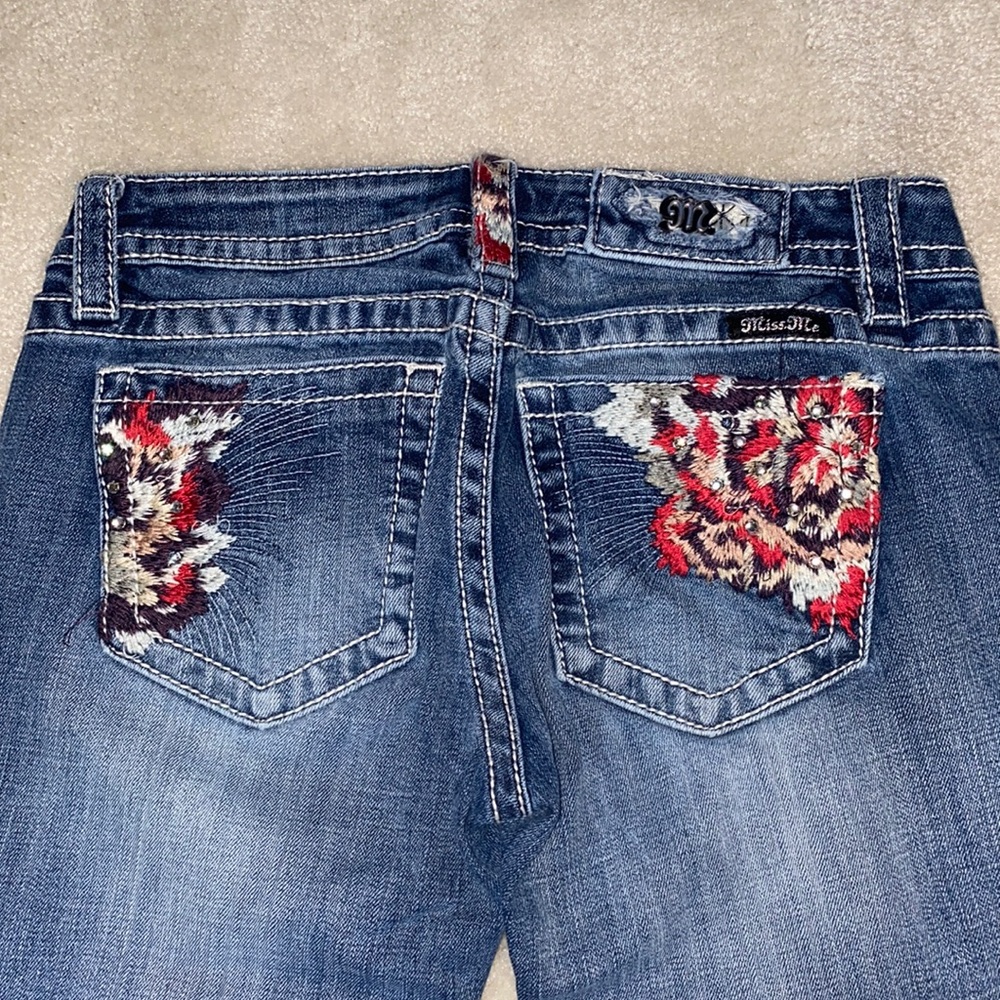 Miss Me signature skinny jeans with multicolored feathered pockets and patches.